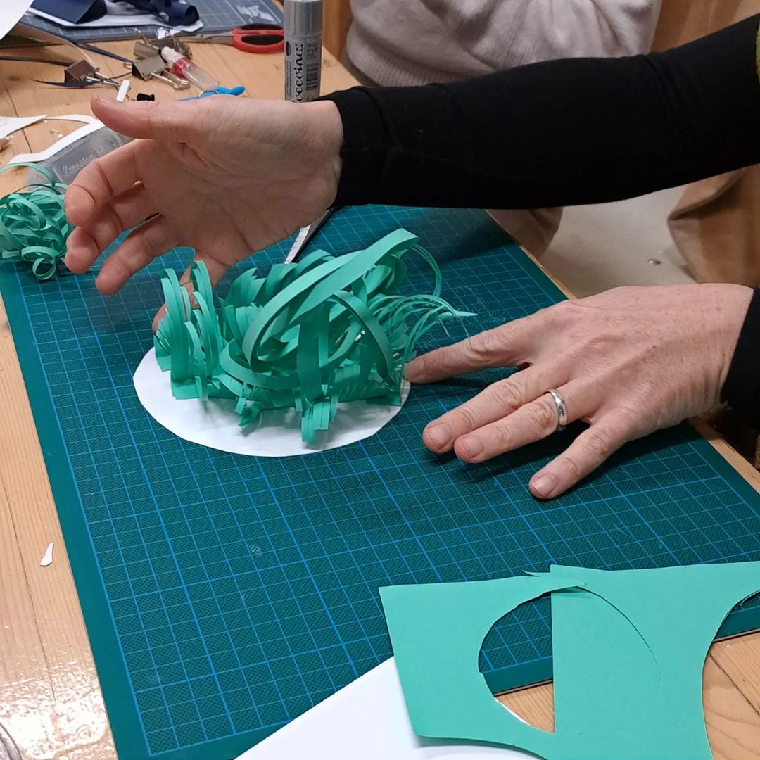 Hands working on a paper sculpture