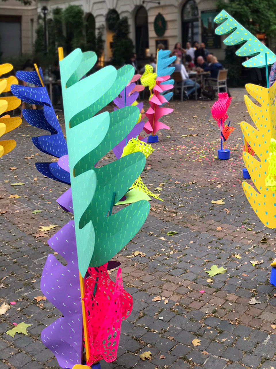 Various colourful paper sculptures standing on the street.