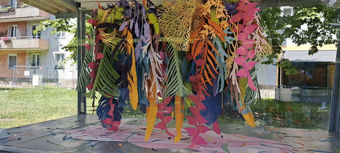 Glass vitrine on public space, that show a paper installation. The installation is a prepresentation of imaginary exotic  flora and botinal